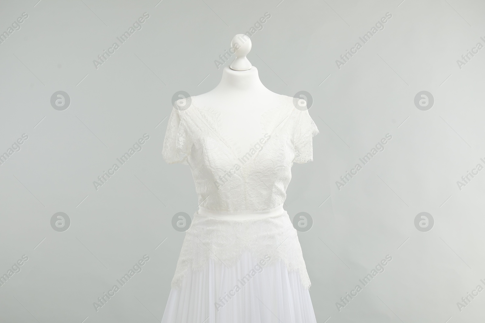 Photo of Mannequin with beautiful wedding dress on light grey background