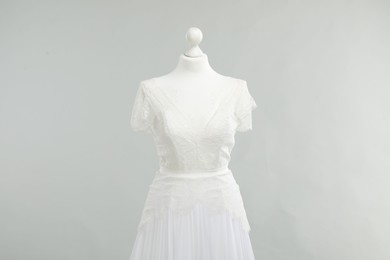 Photo of Mannequin with beautiful wedding dress on light grey background