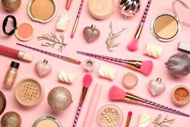 Photo of Different makeup brushes, decorative cosmetics and Christmas decor on pink background, flat lay