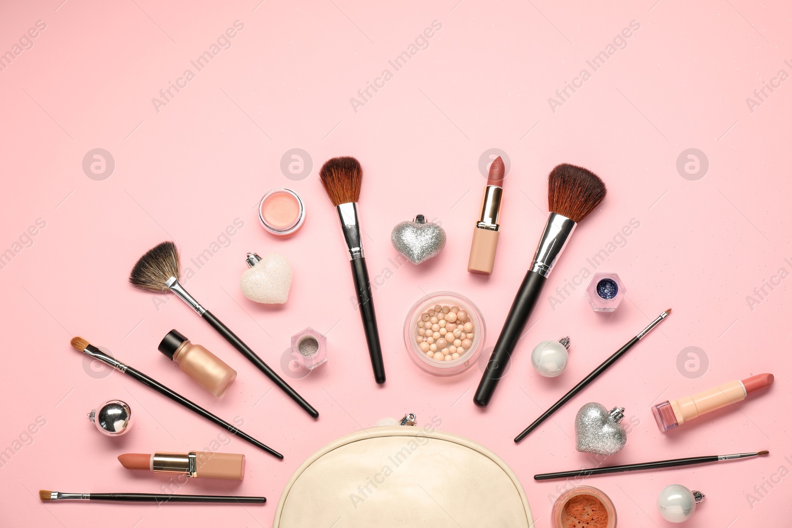 Photo of Cosmetic bag, makeup brushes, decorative cosmetics and Christmas decor on pink background, flat lay