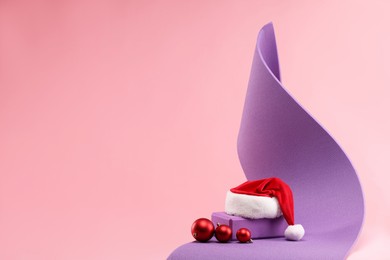 Photo of Yoga mat, Santa hat and baubles on pink background, space for text