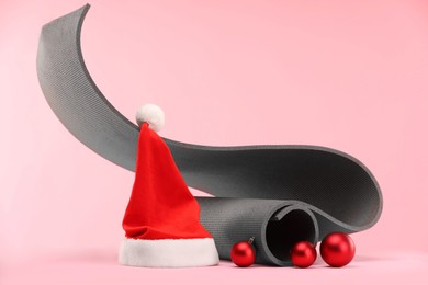 Photo of Yoga mat, Santa hat and baubles on pink background