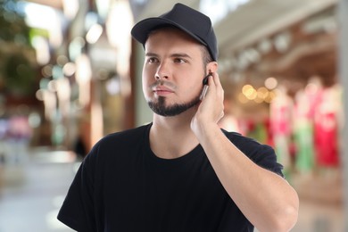 Confident security guard with earpiece in shopping mall