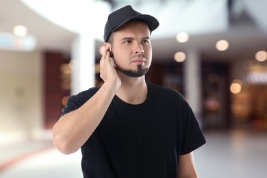 Image of Confident security guard with earpiece in shopping mall