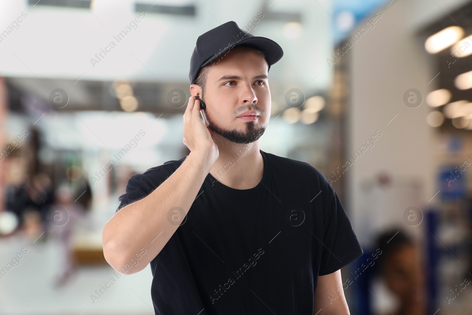 Image of Confident security guard with earpiece in shopping mall