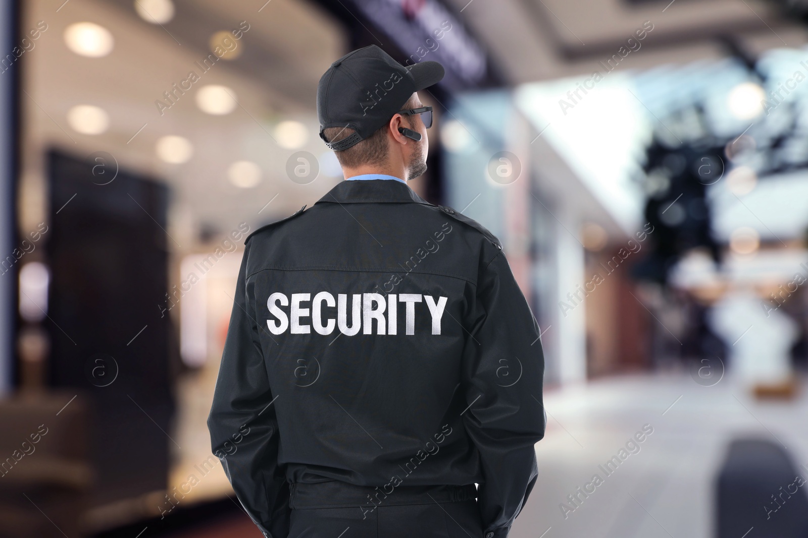 Image of Security guard in uniform and earpiece in shopping mall, back view