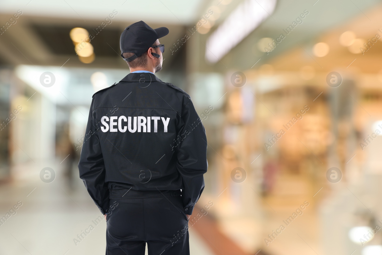 Image of Security guard in uniform and earpiece in shopping mall, back view