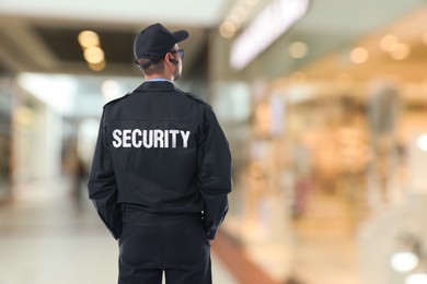 Security guard in uniform and earpiece in shopping mall, back view