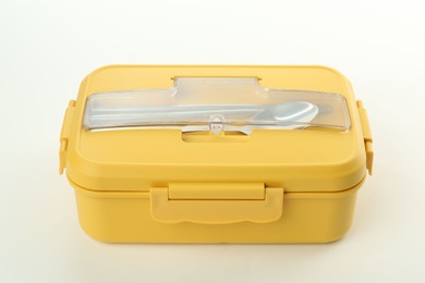 Photo of Yellow lunch box with cutlery isolated on white