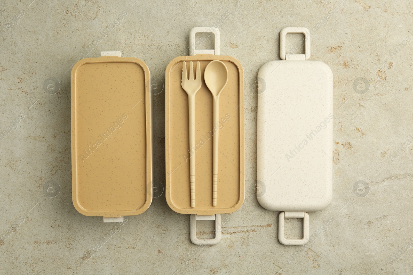 Photo of Compartments of plastic lunch box with cutlery on grey table, top view