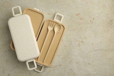 Photo of Compartments of plastic lunch box with cutlery on grey table, top view. Space for text