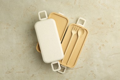 Photo of Compartments of plastic lunch box with cutlery on grey table, top view