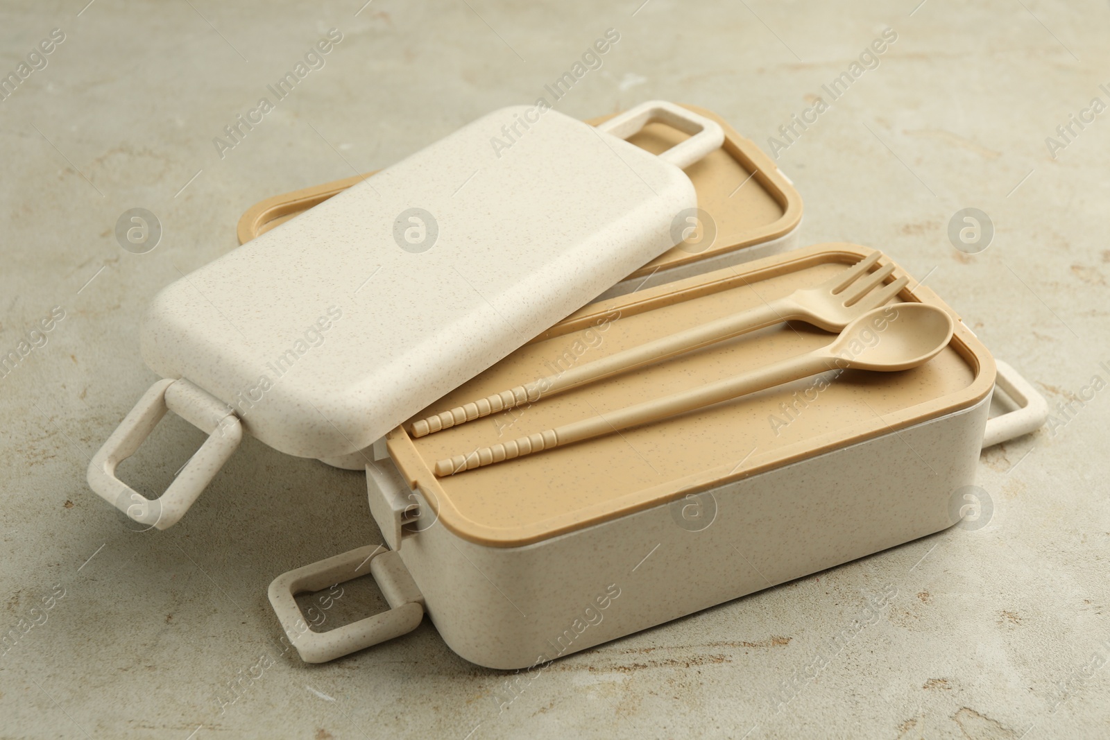 Photo of Compartments of plastic lunch box with cutlery on grey table