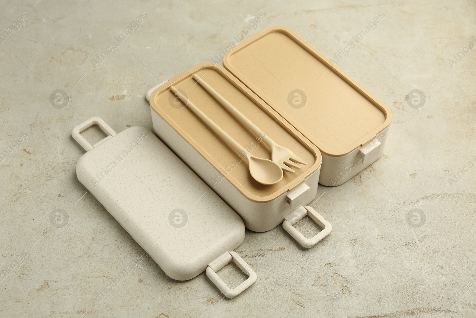 Photo of Compartments of plastic lunch box with cutlery on grey table