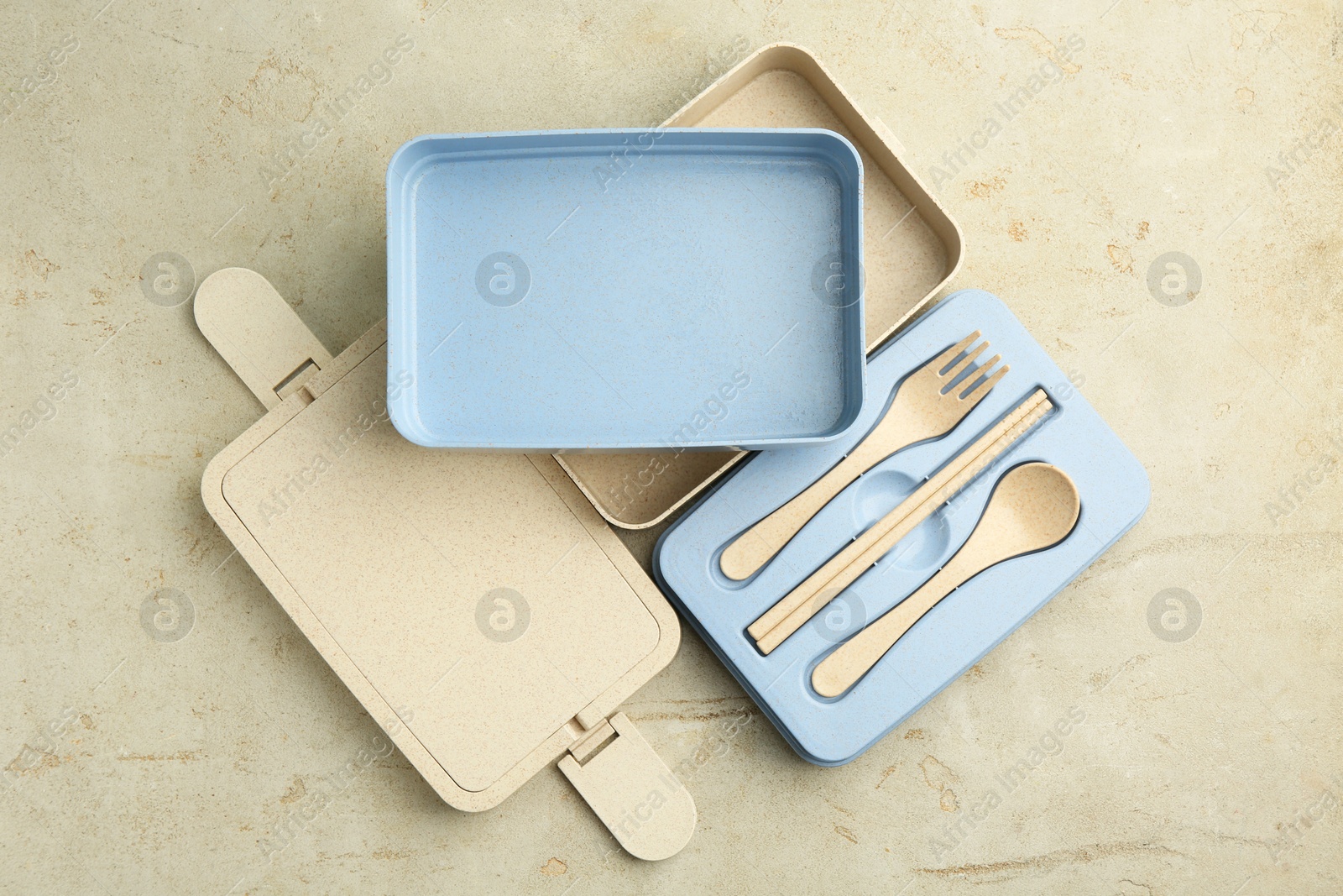 Photo of Compartments of plastic lunch box with cutlery on grey table, top view