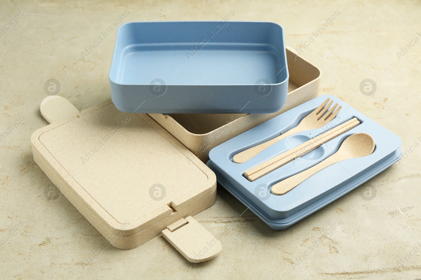 Photo of Compartments of plastic lunch box with cutlery on grey table