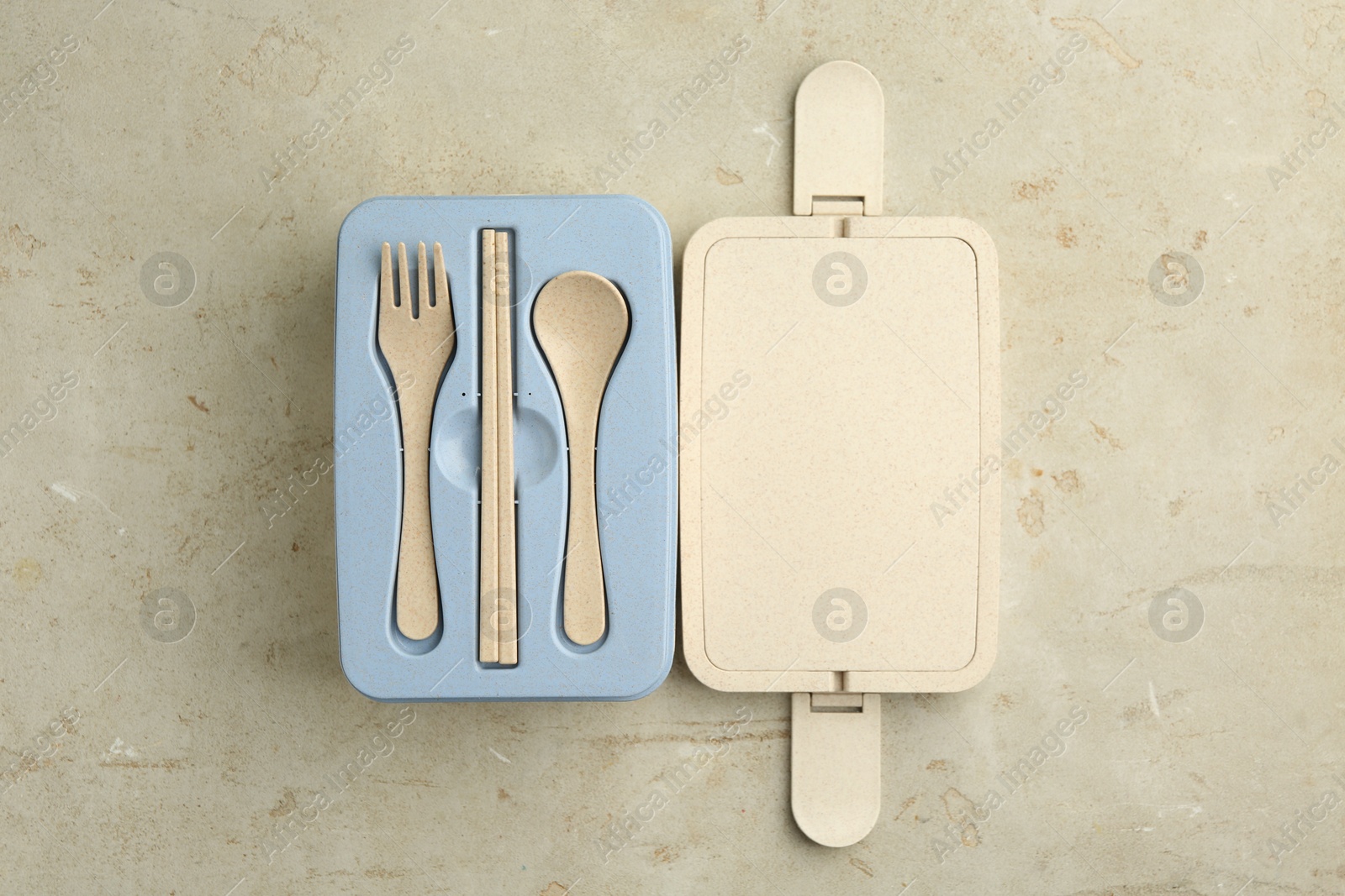 Photo of Plastic lunch box with cutlery and lid on grey table, top view