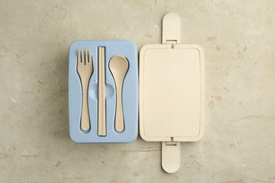 Photo of Plastic lunch box with cutlery and lid on grey table, top view