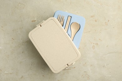 Plastic lunch box with cutlery and lid on grey table, top view