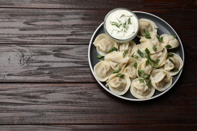 Photo of Delicious pelmeni with green onion served on wooden table, top view. Space for text