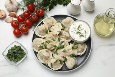 Delicious pelmeni with green onion served on white marble table, flat lay