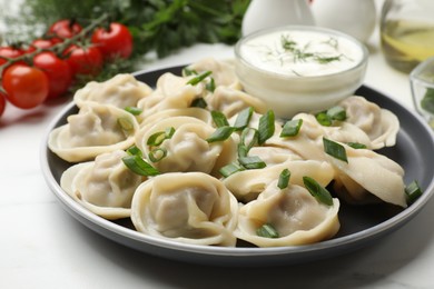 Photo of Delicious pelmeni with green onion served on white table, closeup