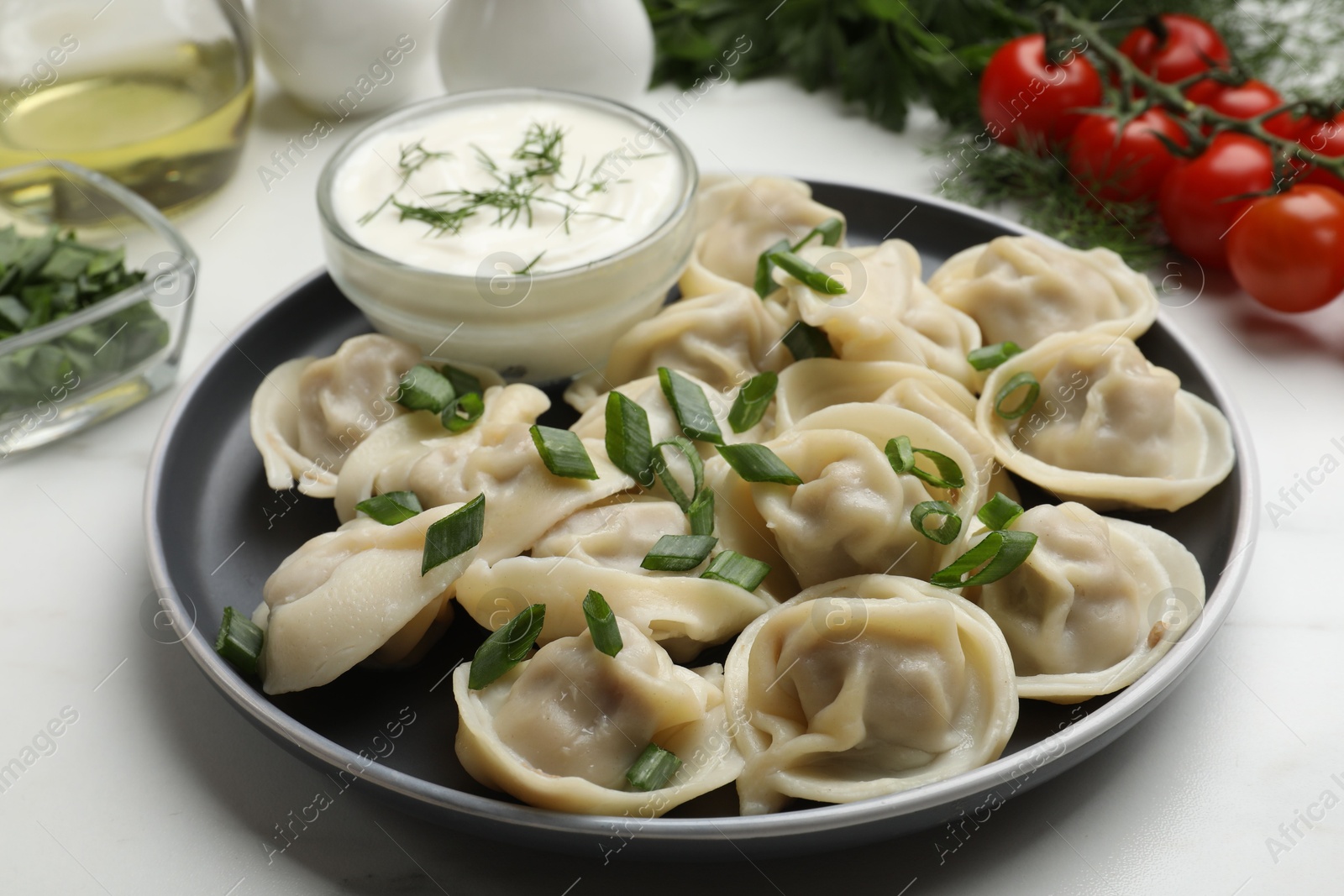 Photo of Delicious pelmeni with green onion served on white table, closeup