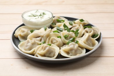 Photo of Delicious pelmeni with green onion served on wooden table, closeup