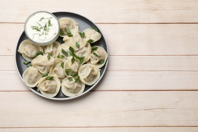 Photo of Delicious pelmeni with green onion served on wooden table, top view. Space for text