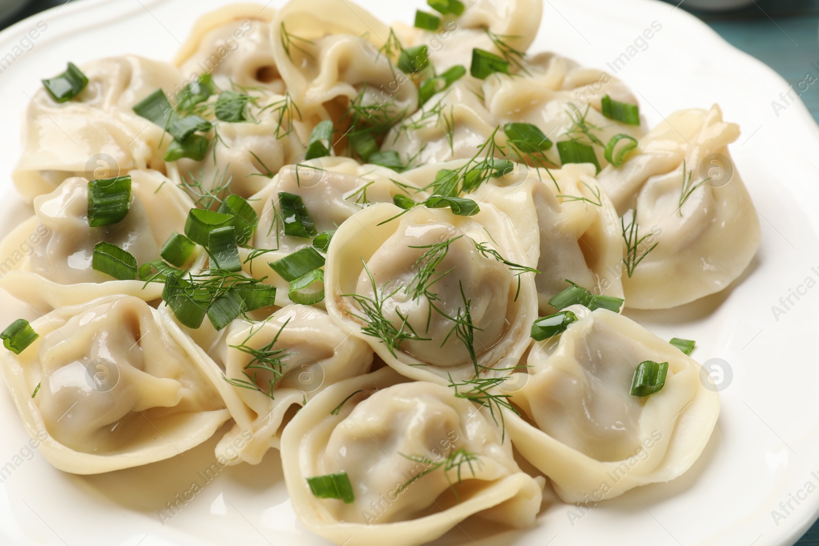 Photo of Delicious pelmeni with green onion and dill on table, closeup