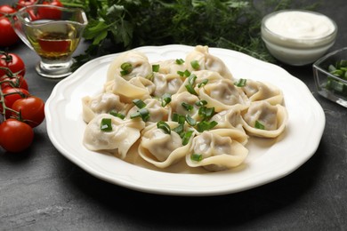 Photo of Delicious pelmeni with green onion served on grey table