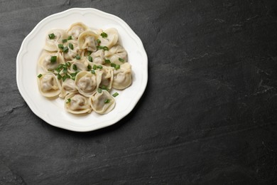 Photo of Delicious pelmeni with green onion on grey textured table, top view. Space for text