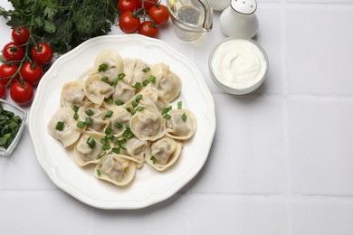 Photo of Delicious pelmeni with green onion served on white tiled table, flat lay. Space for text