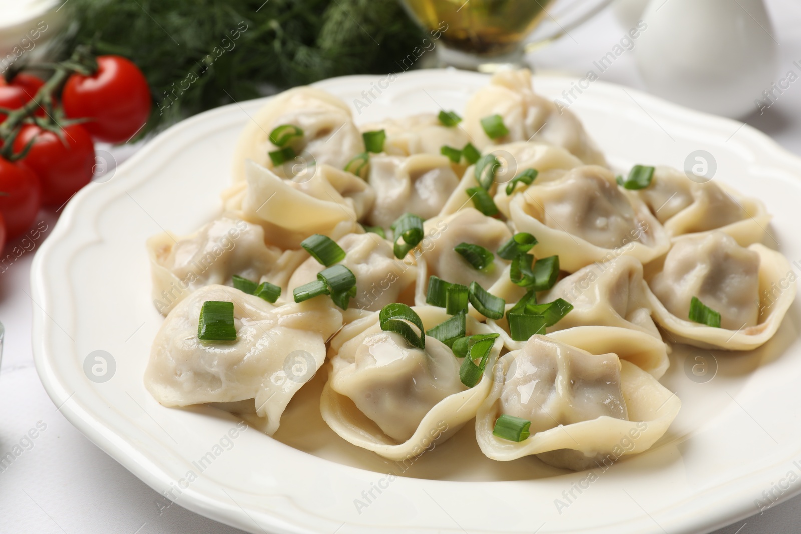 Photo of Delicious pelmeni with green onion on white table, closeup