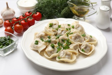 Photo of Delicious pelmeni with green onion served on white table