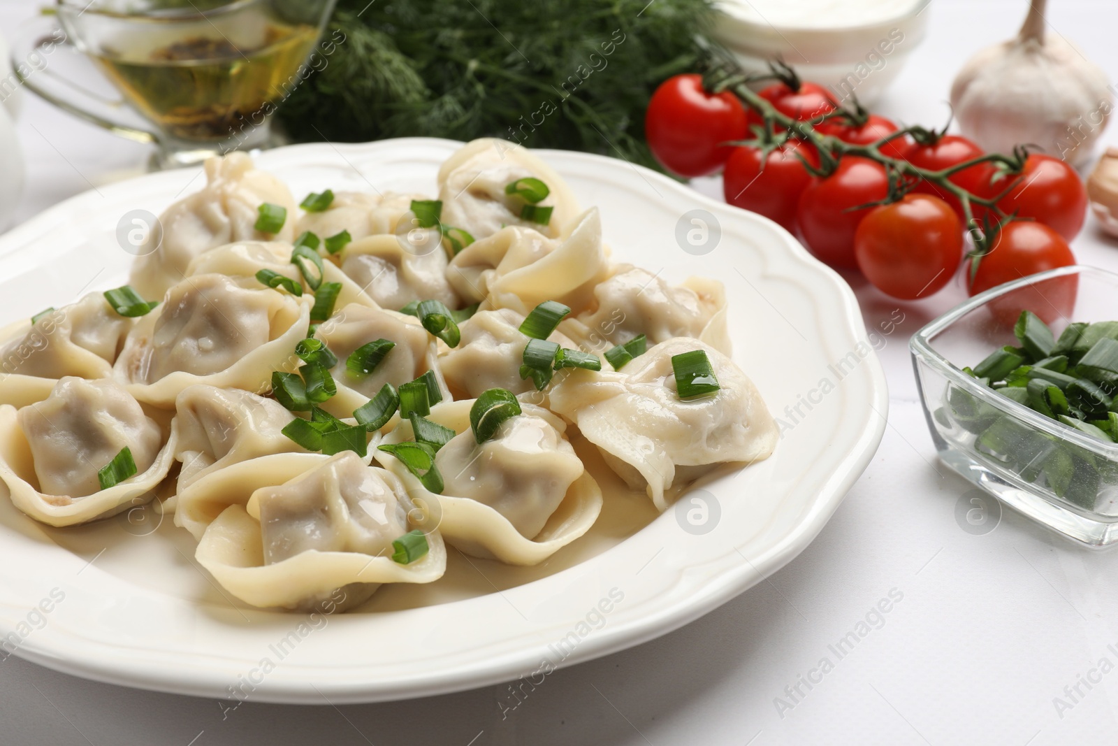 Photo of Delicious pelmeni with green onion served on white table, closeup