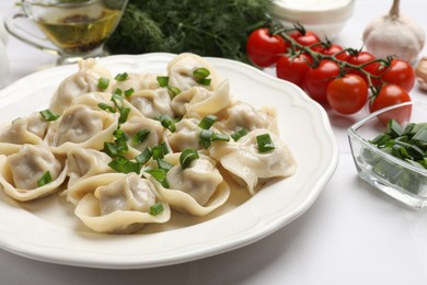 Photo of Delicious pelmeni with green onion served on white table, closeup