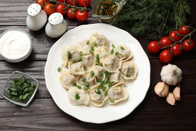 Photo of Delicious pelmeni with green onion served on wooden table, flat lay