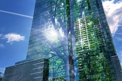 Image of Environment preservation. Double exposure of modern building and tree against blue sky, low angle view