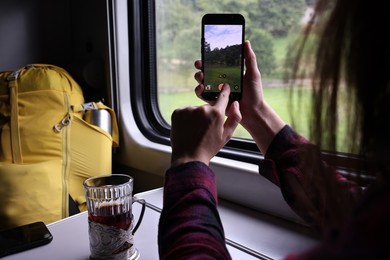 Young woman taking photo with smartphone in train, closeup