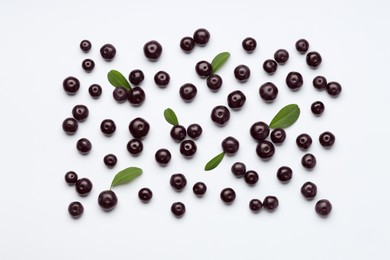 Photo of Ripe acai berries and leaves on white background, flat lay