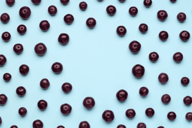 Photo of Frame of ripe acai berries on light blue background, flat lay. Space for text