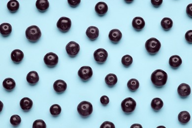 Photo of Ripe acai berries on light blue background, flat lay