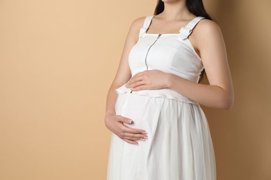 Photo of Young pregnant woman on beige background, closeup. Space for text