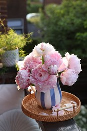 Photo of Beautiful pink peony flowers in vase on balcony railing outdoors