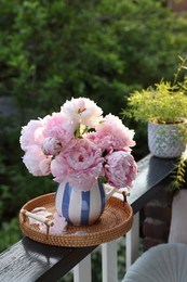 Beautiful pink peony flowers in vase on balcony railing outdoors