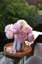 Beautiful pink peony flowers in vase on balcony railing outdoors