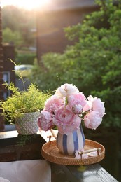 Beautiful pink peony flowers in vase on balcony railing outdoors