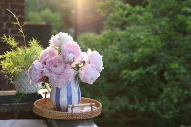 Photo of Beautiful pink peony flowers in vase on balcony railing outdoors. Space for text