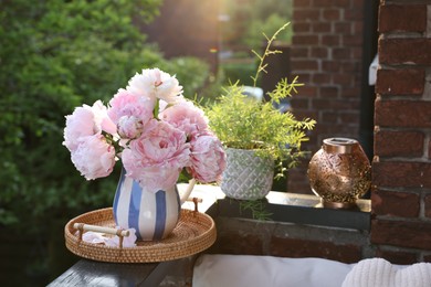 Beautiful pink peony flowers in vase on balcony railing outdoors